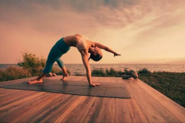 Pessoa praticando yoga com postura de alongamento para alívio da dor na coluna.